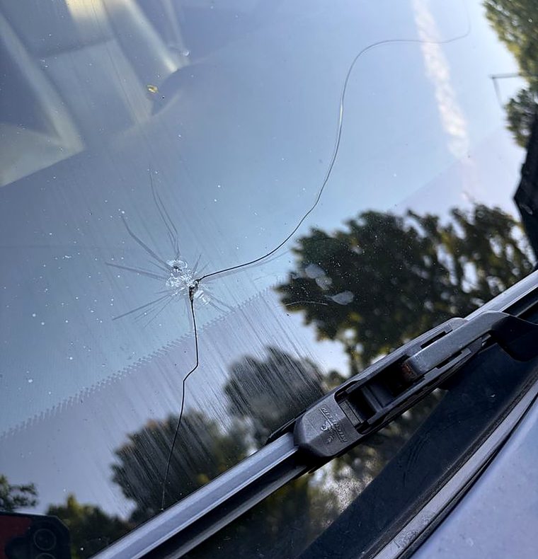 Rock chip on a windshield with a long crack already running away from the impact point toward the wiper cowl