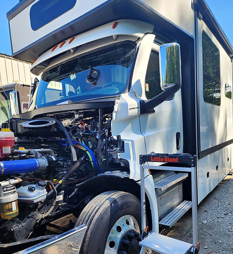 Freightliner Cascadia commercial cab with the hood tilted forward during a heavy vehicle windshield replacement