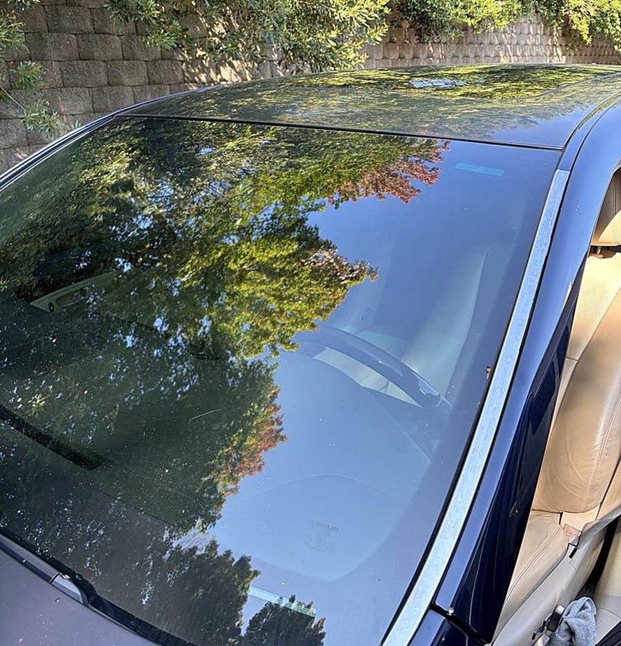 Completed windshield replacement on a dark blue sedan, clean glass and correctly seated mouldings